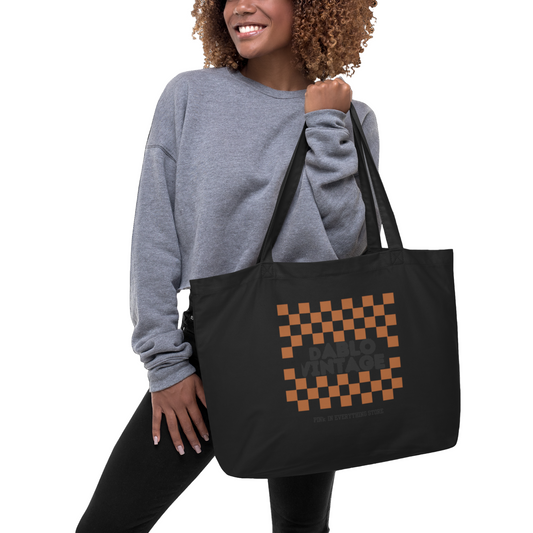 Woman holding a black tote bag with a checkered pattern and text on a white background